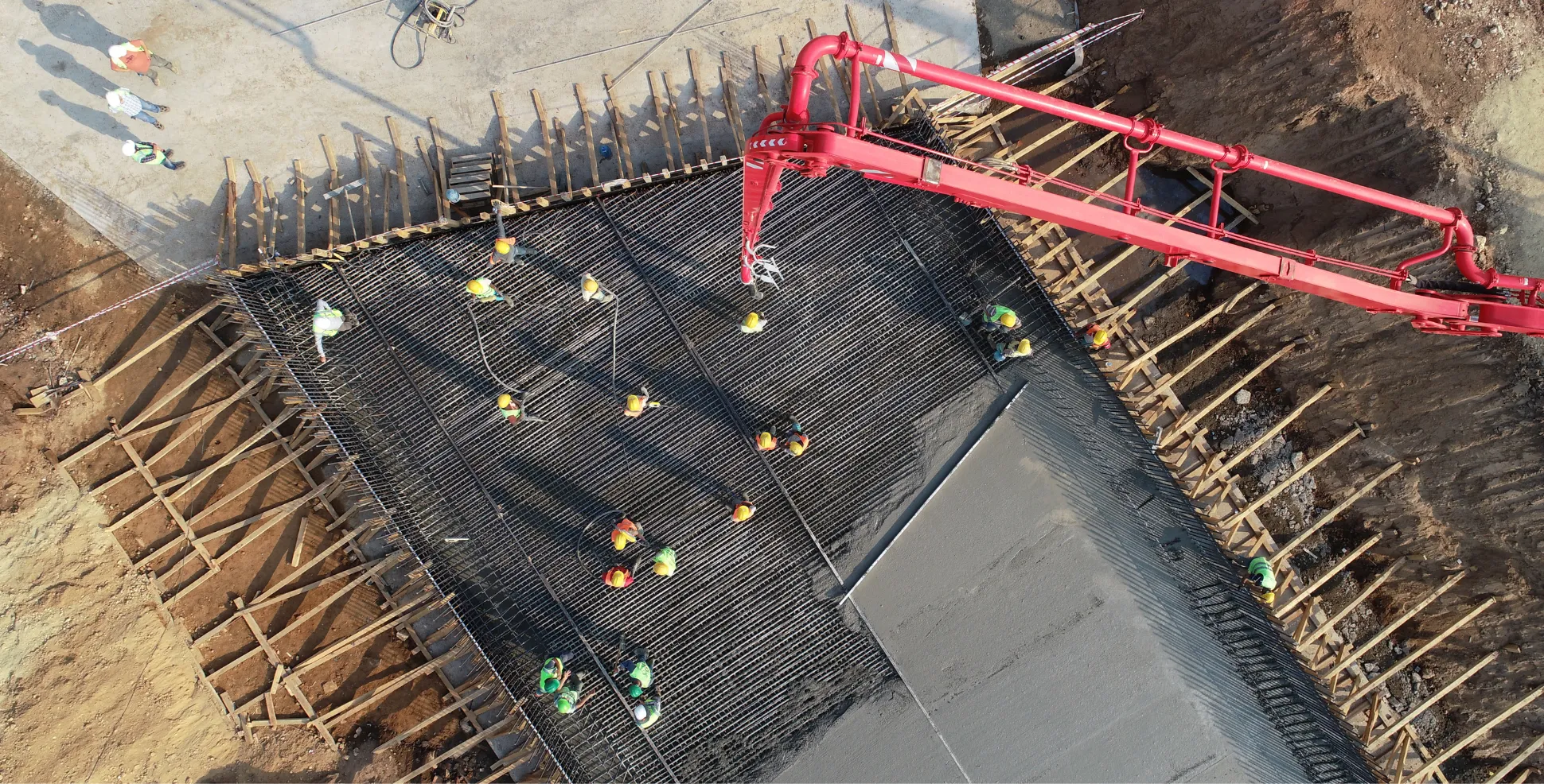 Boom pump pouring structural concrete over heavy rebar grid on a commercial construction site in Los Angeles